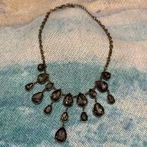 Gold-tone statement bib necklace with smoky gray rhinestone teardrops. 